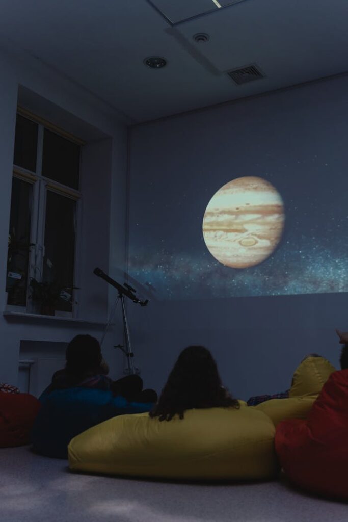 Students watch a projected image of Jupiter in a dark classroom setting, enhancing their astronomy learning.